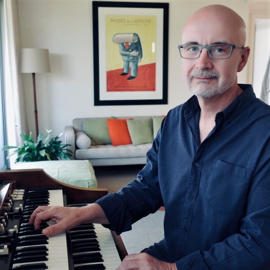 Photo of Darren Heinrich sitting at a Hammond Organ, his hands resting on the keys, looking at the camera.