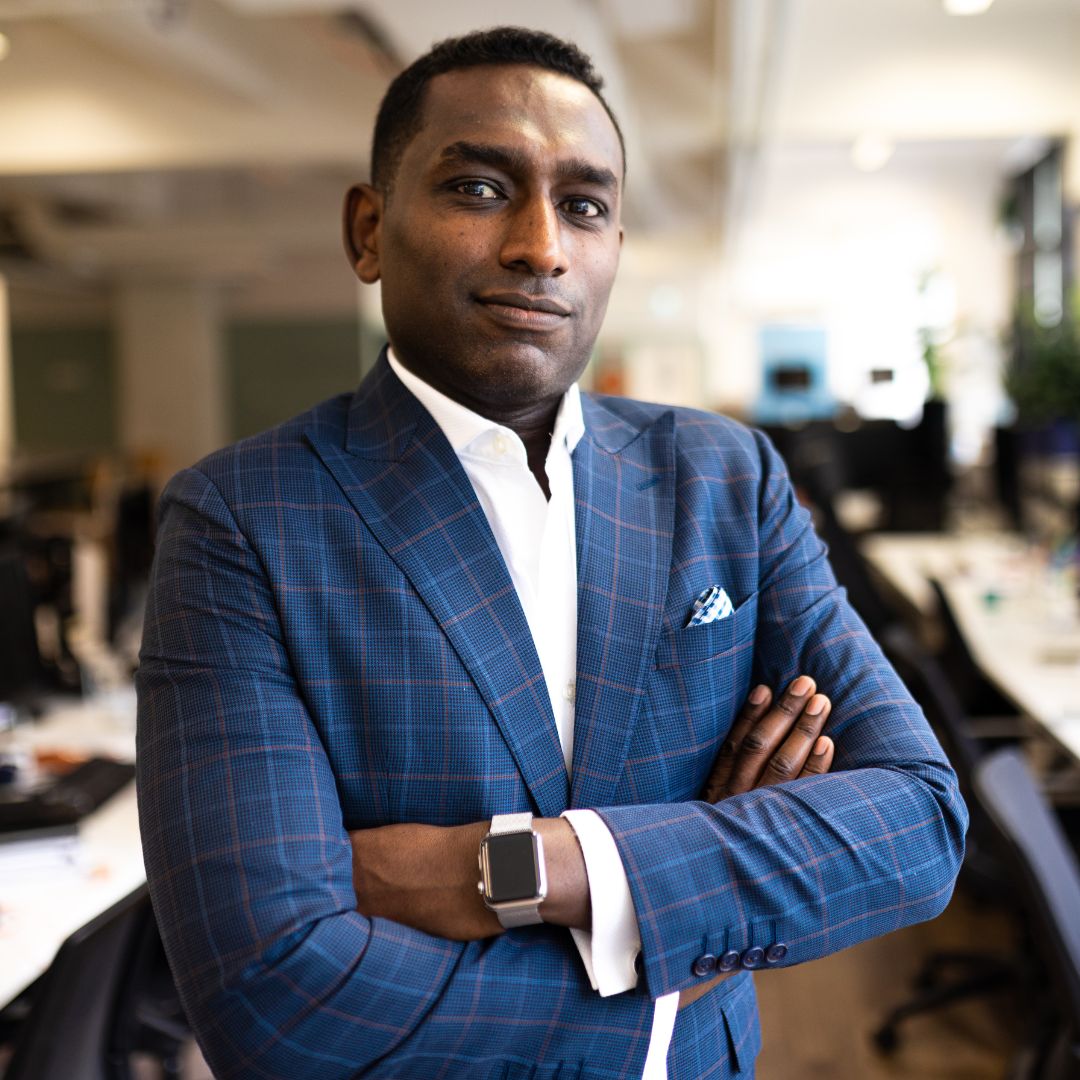 Photo of Ibrahim, standing in an office wearing a blue suit.