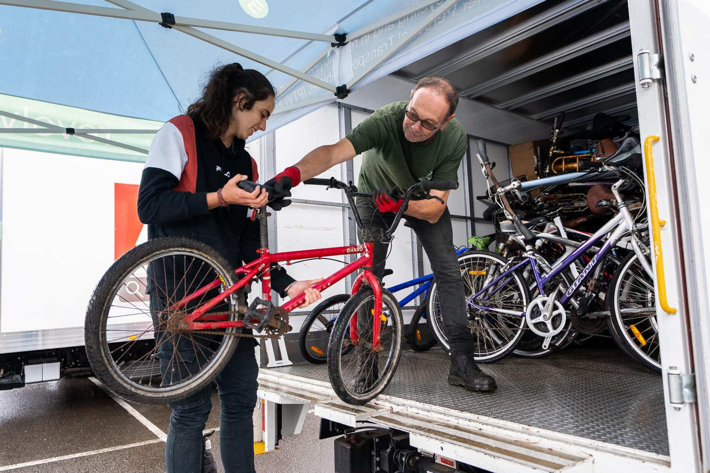 Person grabbing a bike from another person and putting in truck