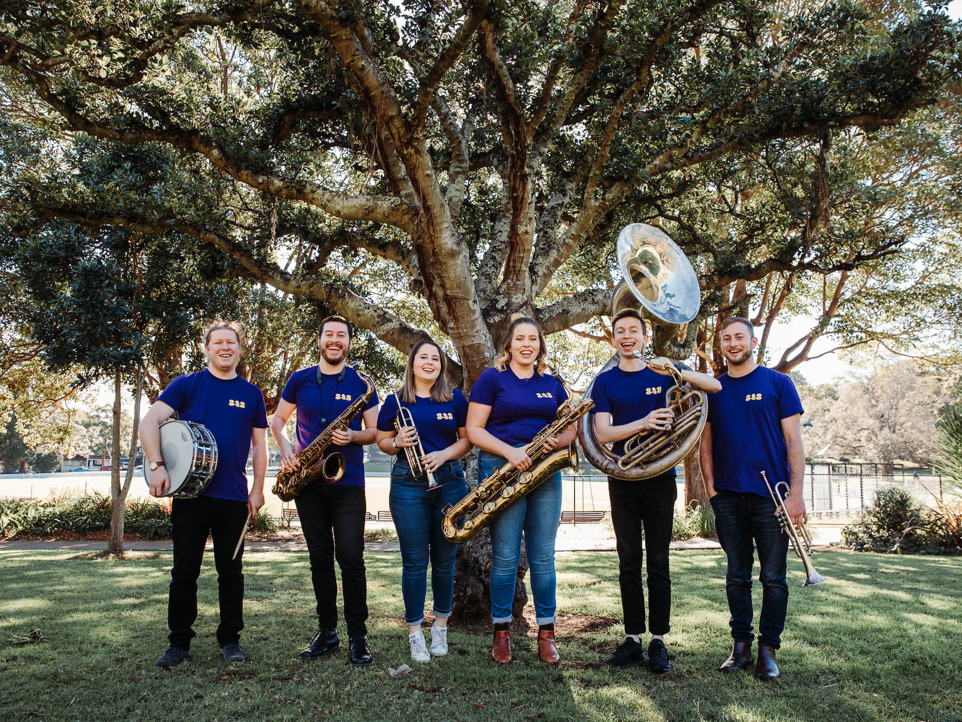 brass band musicians under a tree