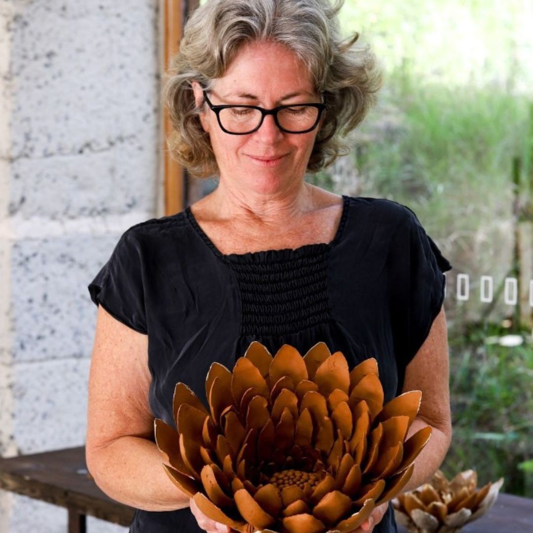 Michelle stands holding a ceramic flower