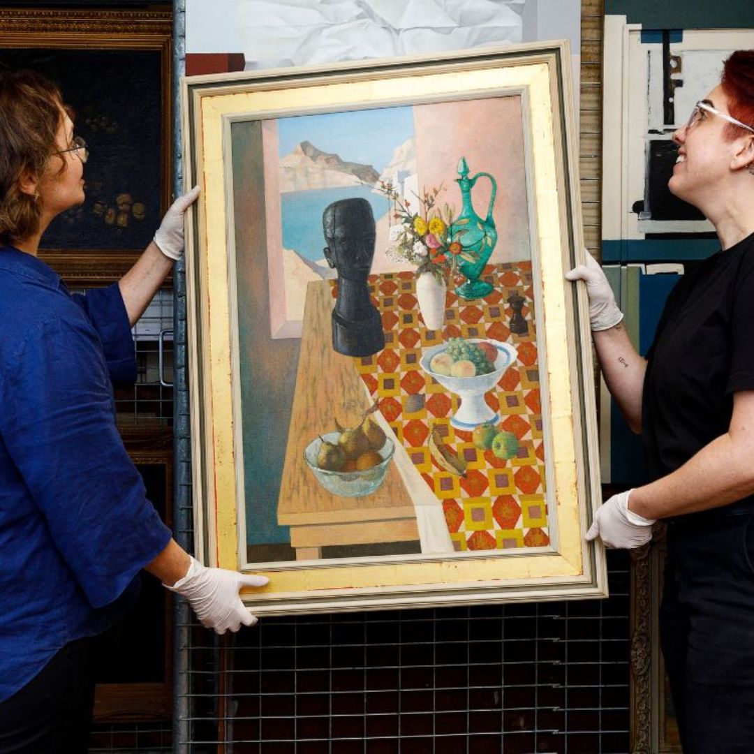 two curators hold a painting in the collection store