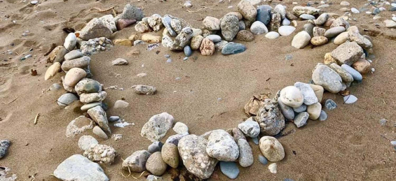 Stones on sand in shape of a heart