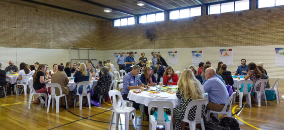 people sitting around tables undertaking community engagement activities 