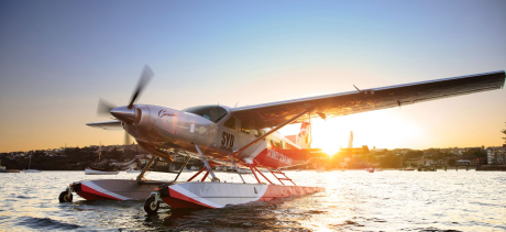 A seaplane on the water with the sun setting behind