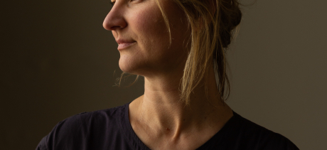 portrait of Kate Butcher, a blond woman wearing a black top with angular zips, looking to the left with high contrast lighting