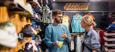 Shop keeper standing at shop Pace Athletic with customer