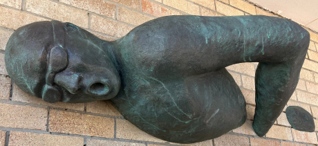 Metal artwork of a swimmer emerging from brick wall