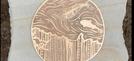 metal disc artwork with whales engraved on it