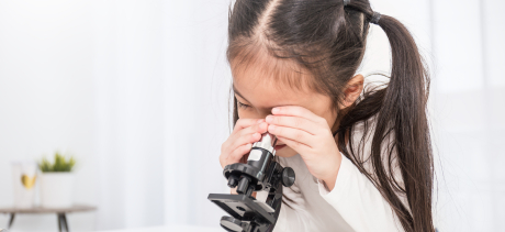 Young girl looking through microscope