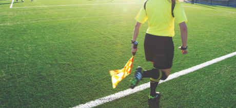 An umpire on Cromer Park pitch holding a flag