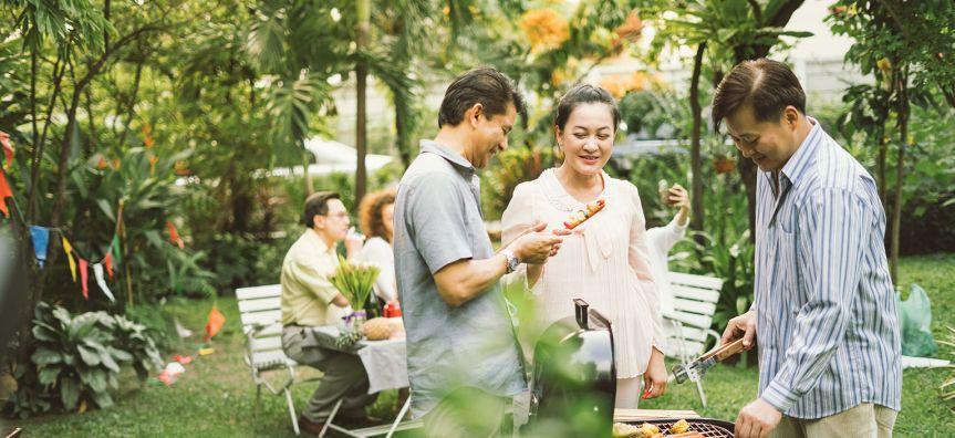 Women and two men are outside at a bbq