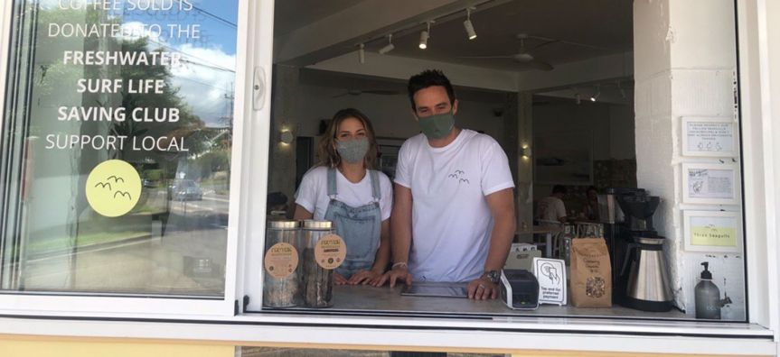 two people behind a cafe counter wearing face masks