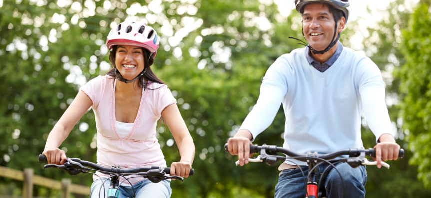 Two people on bikes riding and wearing helmets