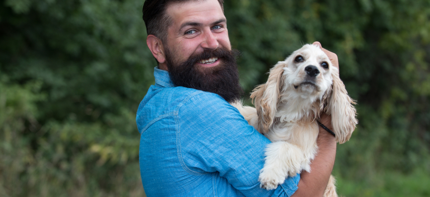 bearded man holding light coloured dog