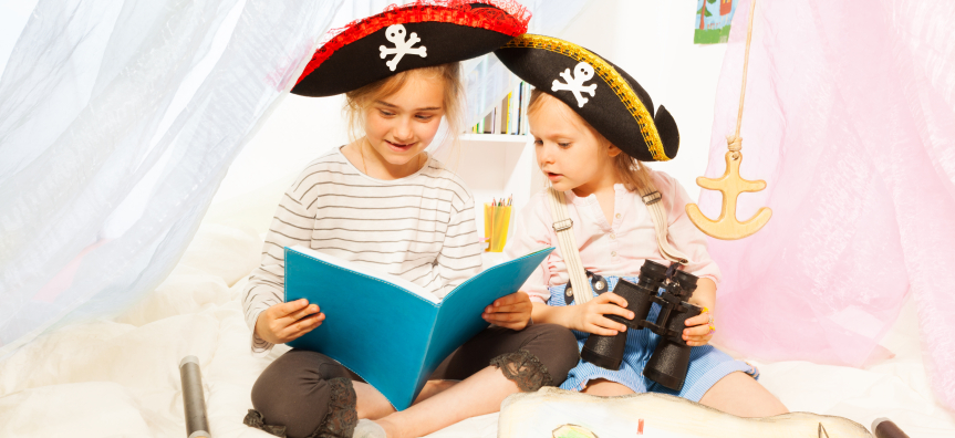 Two girls reading together in pirate hats