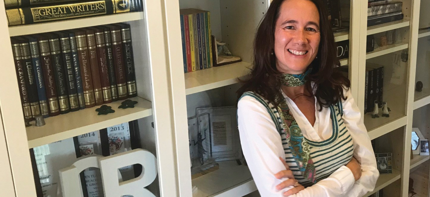 Zena Shapter standing in front of bookcase filled with books