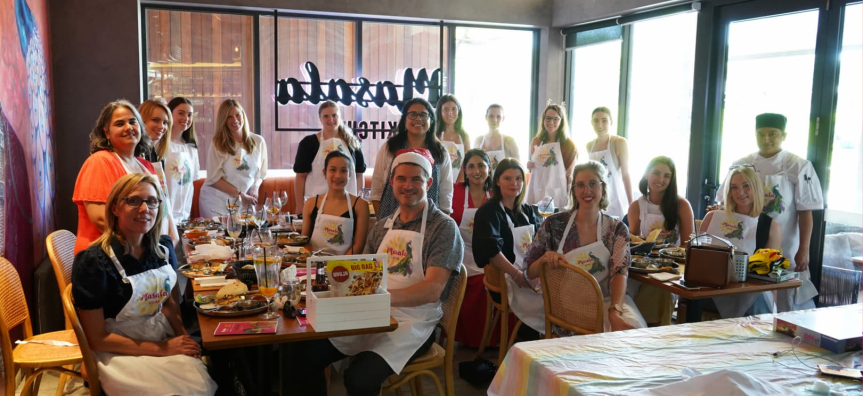 A group of cooking class participants grouped around tables