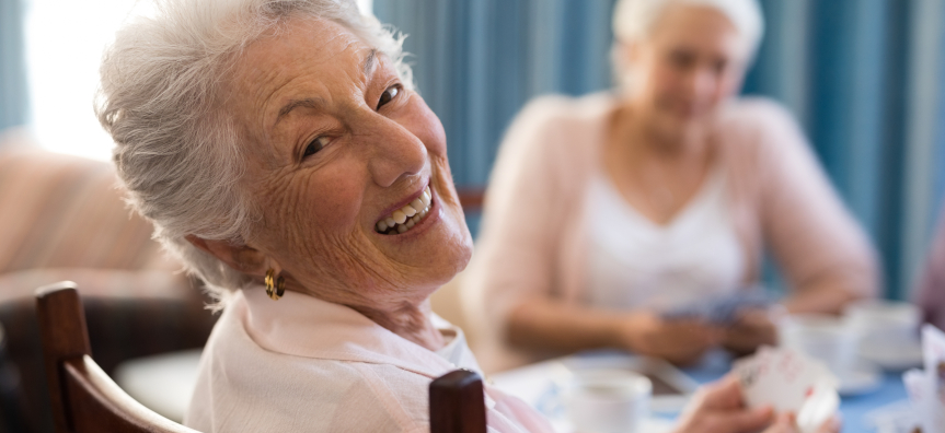 Senior woman playing cards with friends at table in nursing home.jpg