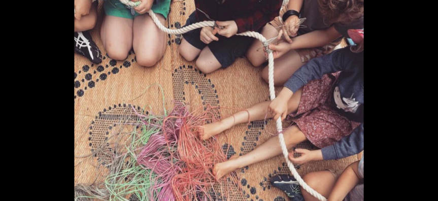 Ngumpie weaving on floor with children