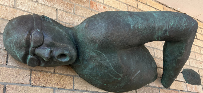 Metal artwork of a swimmer emerging from brick wall