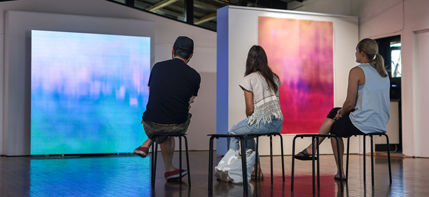 People sitting on a seat watching a light art installation