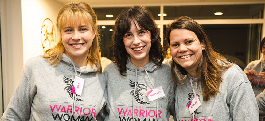 Three people smiling with jumpers that say Warrior Women Foundation
