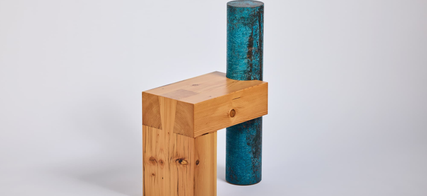 A wooden sculpture with a blue cylinder atop, made up of a blend of materials.