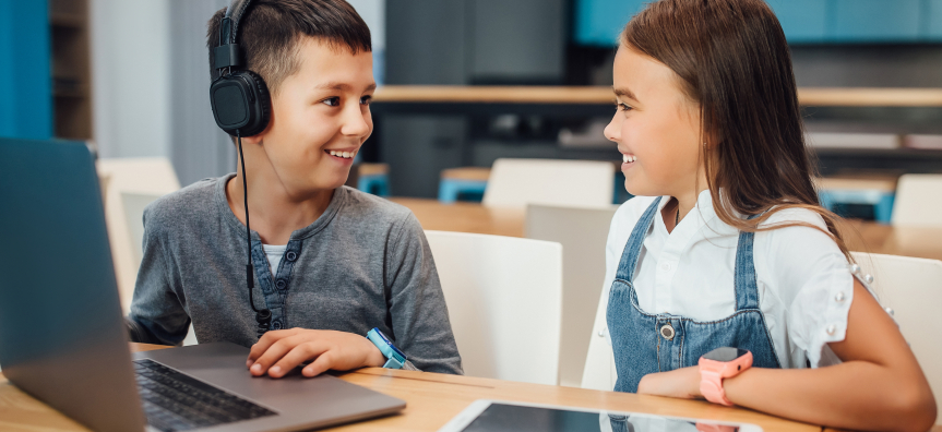 Two young children smiling at each other. 