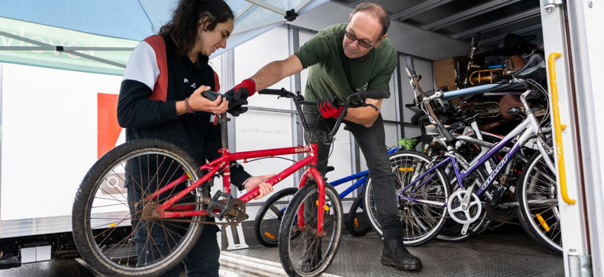 Person grabbing a bike from another person and putting in truck