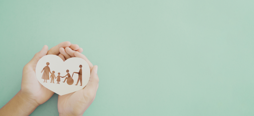 silhouette of a family containing a wheelchair user, inside a paper heart shape.