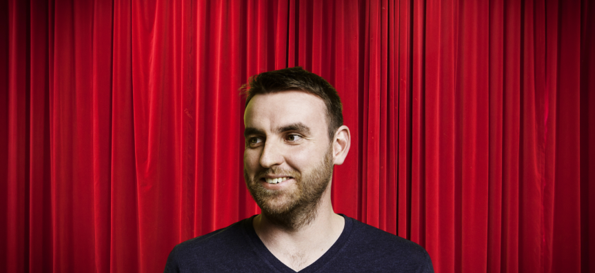 man in front of a red curtains