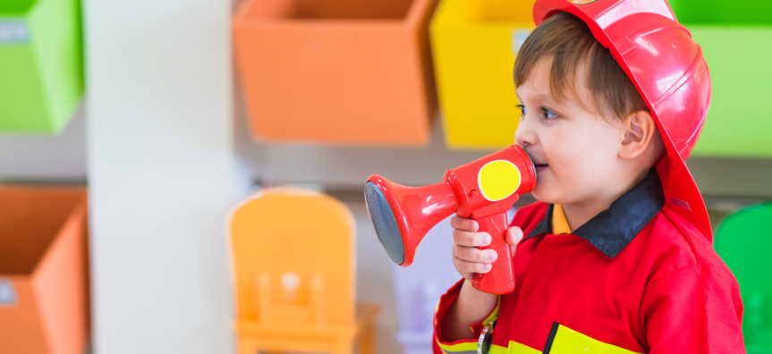 Child dressed in Fire Fighter costume, holding a plastic speakerphone