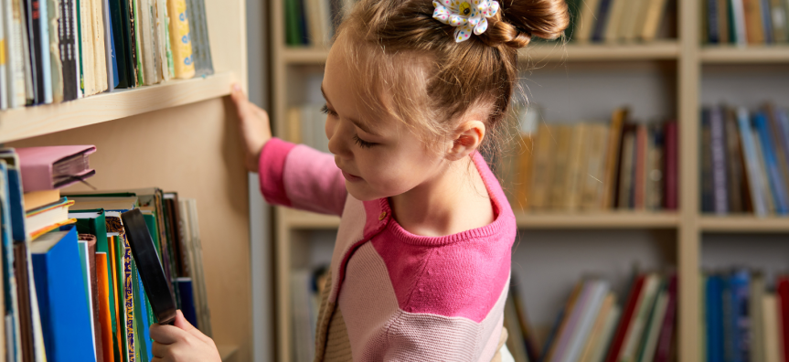 Child looking at bookshelves with a magnifying glass