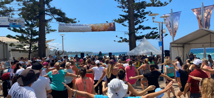 People participating in a stretching exercise at Manly Health and Wellness Day