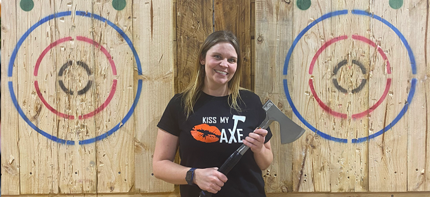 A Kiss My Axe worker in Brookvale holds an axe in front of two targets