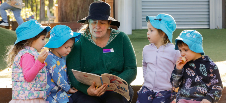 Children reading a book with an adult