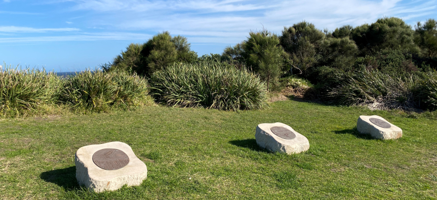 Three bronze artworks of whales on top of a sandstone slab