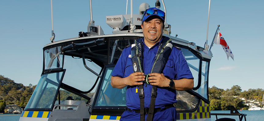 Jimmy Arteaga, volunteer at Marine Rescue Broken Bay stands in uniform in front of the rescue boat