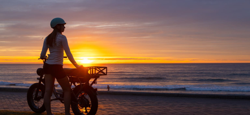 Teenager on her e-bike by the beachfront at sunrise