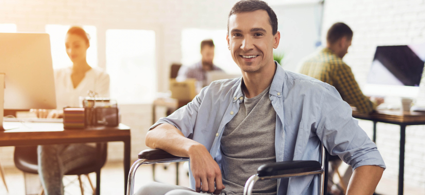 A smiling man sitting in his wheelchair in an office space