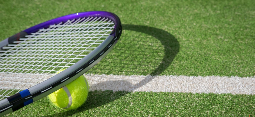 Tennis racket and ball on turf