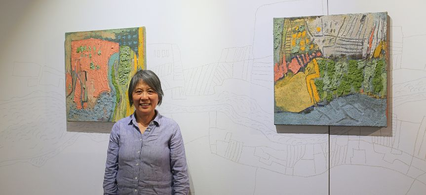 Mei Zhao standing in front of her paintings in a gallery space