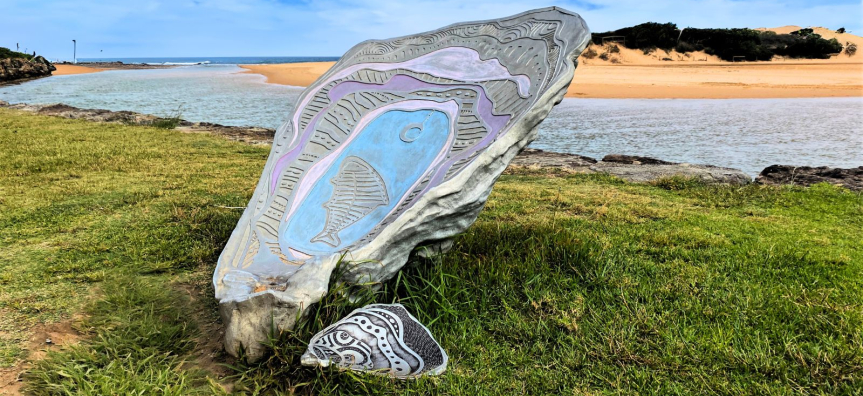 Metal shell artwork on grass next to beach