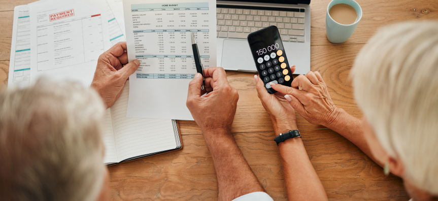 two people using a calculator and looking at spreadsheets