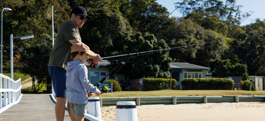 man and small boy fishing on jetty at Currawong Beach Cottages, Pittwater
