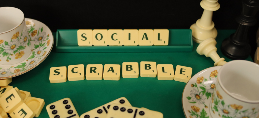 scrabble tiles spelling out social scrabble, with some tea cups and chess pieces