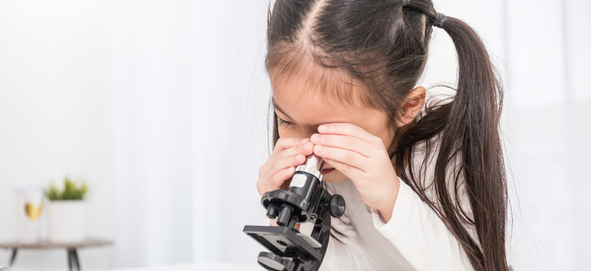 Young girl looking through microscope