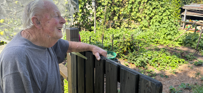 old man leaning on garden fence