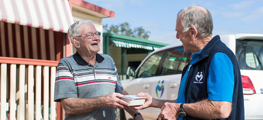 A Meals on Wheels volunteer and client smile together